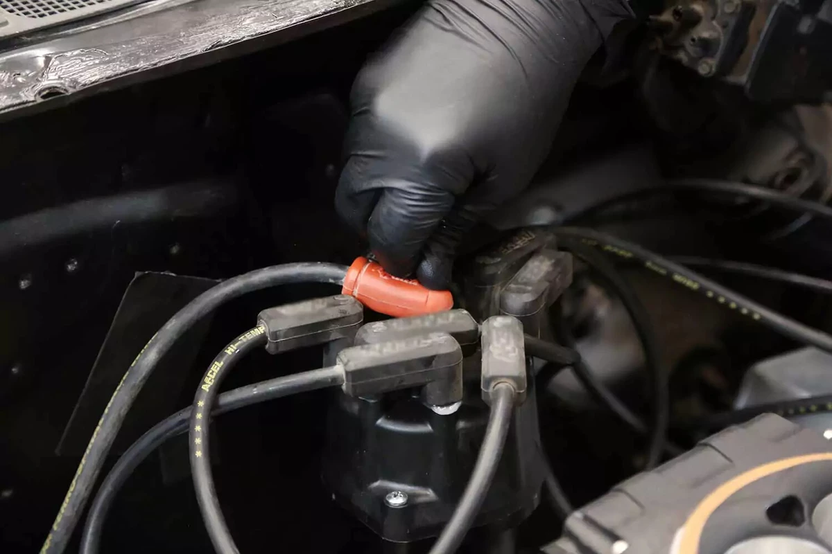 A mechanic attaches the coil wire to the distributor cap.