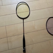 Babolat badminton racket with black and yellow strings, cracked in one place.