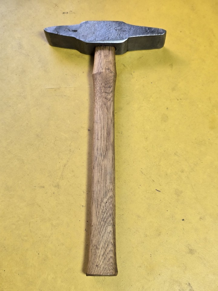 A 600g masonry hammer with an unusual stamped head — the kind of brutalist hand tool that looks like it belongs in a blacksmith's museum.