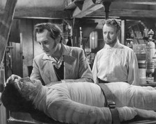 Baron Frankenstein played by Peter Cushing leans over the monster - Old Photo