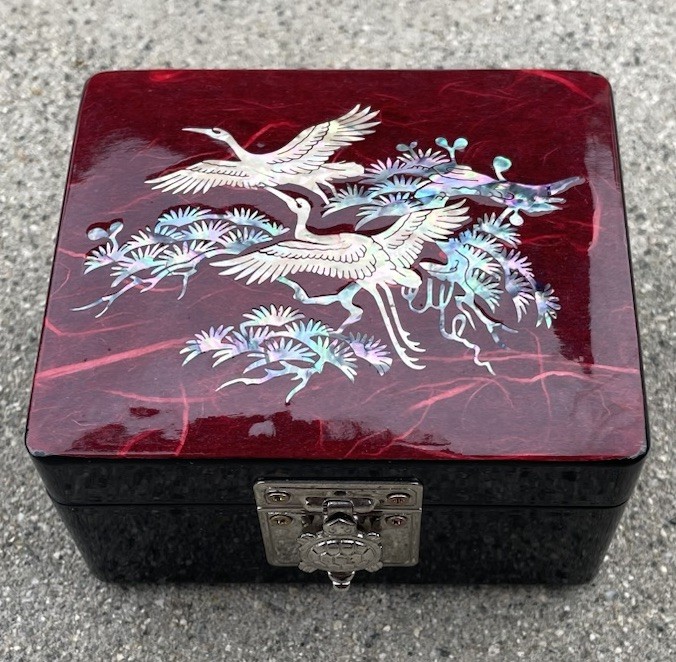 Black lacquer jewelry box with inlaid shell storks, red velvet interior, and turtle mirror-image
