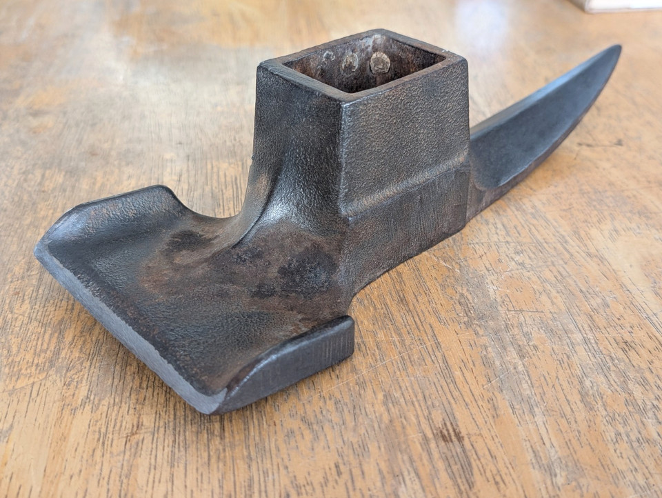 A hand-forged, patented shipwright's lipped adze head — the kind of specialized maritime trade tool that looks like functional sculpture on a workshop wall.