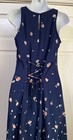 Navy blue sleeveless midi dress with small white floral print, lace-up front detail, and fitted bodice on mannequin.