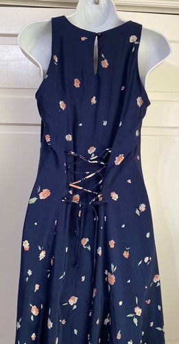 Navy blue sleeveless midi dress with small white floral print, lace-up front detail, and fitted bodice on mannequin.