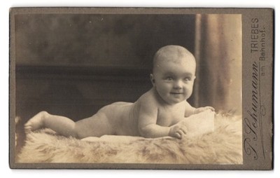 Fotografie I. Schumann, Triebes, Am Bahnhof, lächelndes Kleinkind im Fell liege 