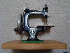 ANTIQUE VINTAGE MINIATURE SINGER SEWING MACHINE. COMES WITH MODERN OAK BASE