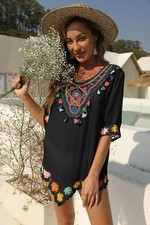 Black caftan-style tunic with floral embroidery and colorful tassels.