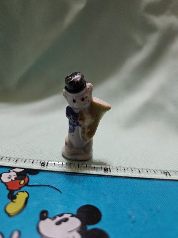Miniature ceramic bear wearing a black top hat/a blue jacket playing instrument.