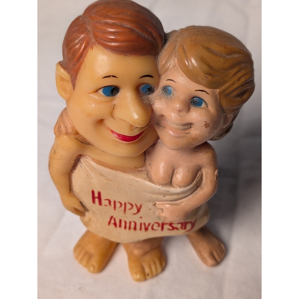 A kitschy rubber anniversary couple figurine that walks the perfect line between sincere and satirical — the kind of vintage tchotchke that earns a permanent spot on a shelf.