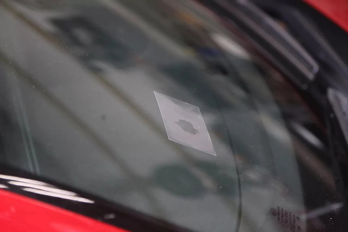 A clear plastic top slip covers the repaired spot of a windshield.