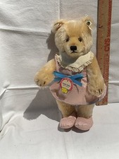 Steiff Teddy Bear Baby color is blonde brown eyes and black nose in a pink dress