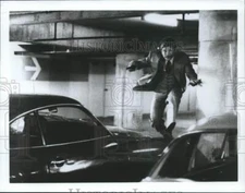 1983 Press Photo Charles Bronson leaps over a car in a movie scene - nop10909