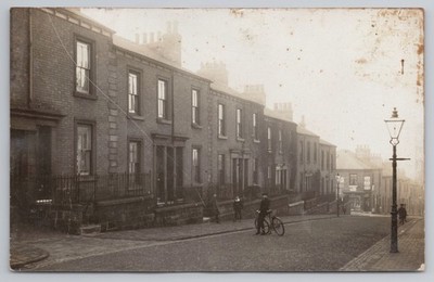 RPPC unbekannte Straßenszene Reihenhäuser Mann mit Fahrrad Gaslampe um 1910
