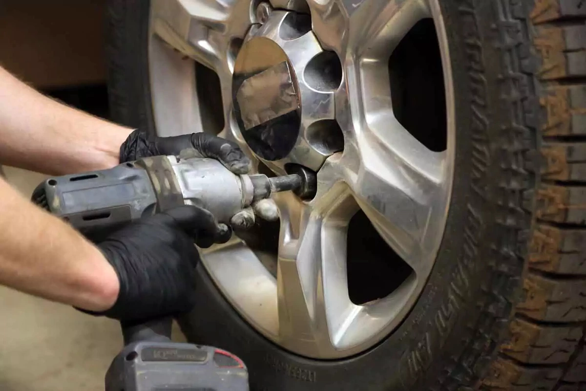 A mechanic tightens a lug nut with an impact wrench.