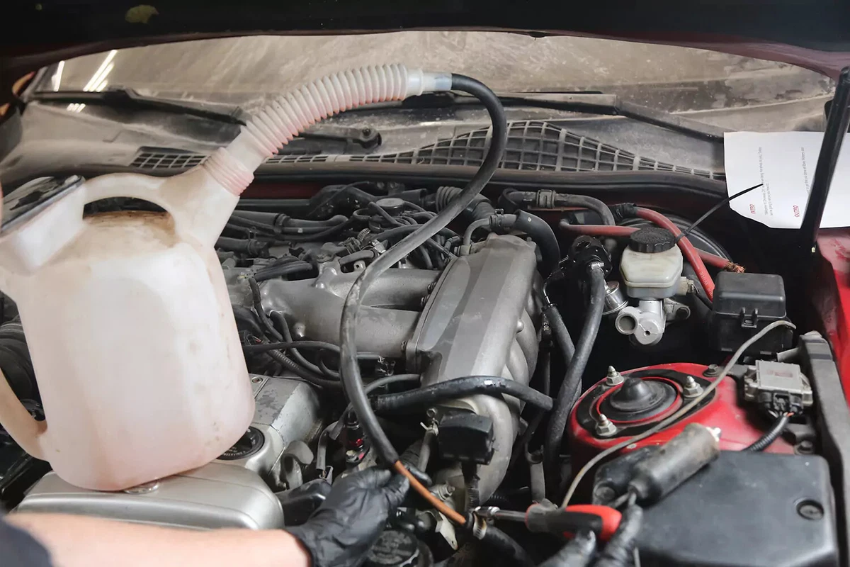 A large clear container attached to the return line of a vehicle's power steering reservoir.