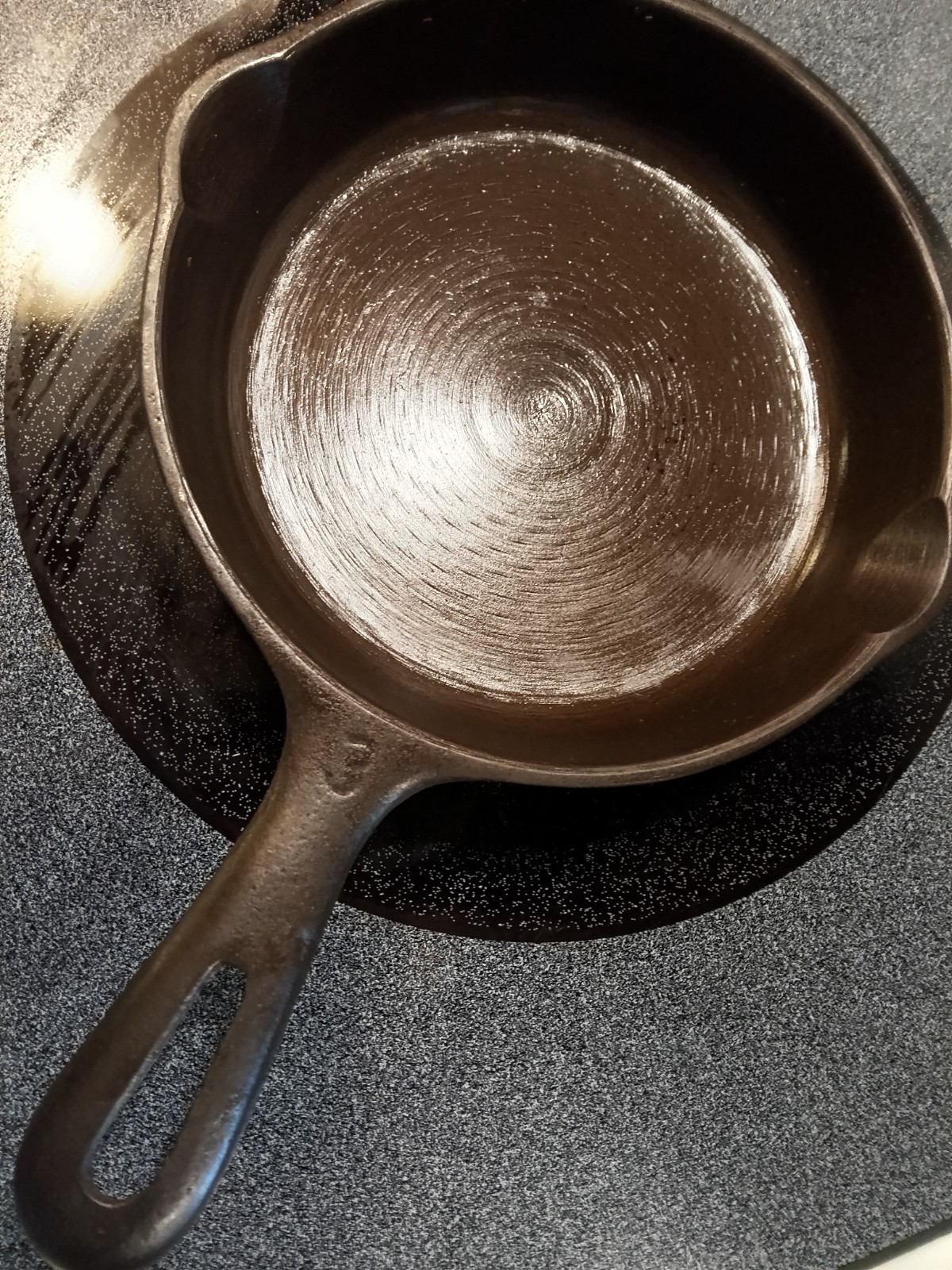 Small unmarked cast iron skillet, likely Wagner, with a single pour spout and loop handle.