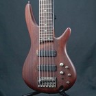 Ibanez SR506-BM used w/soft case, dark wood with gold hardware, six-string bass, on black stand.