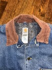Blue denim Carhartt C59 chore coat with brown suede collar, gray lining, and visible Carhartt logo patch on chest.