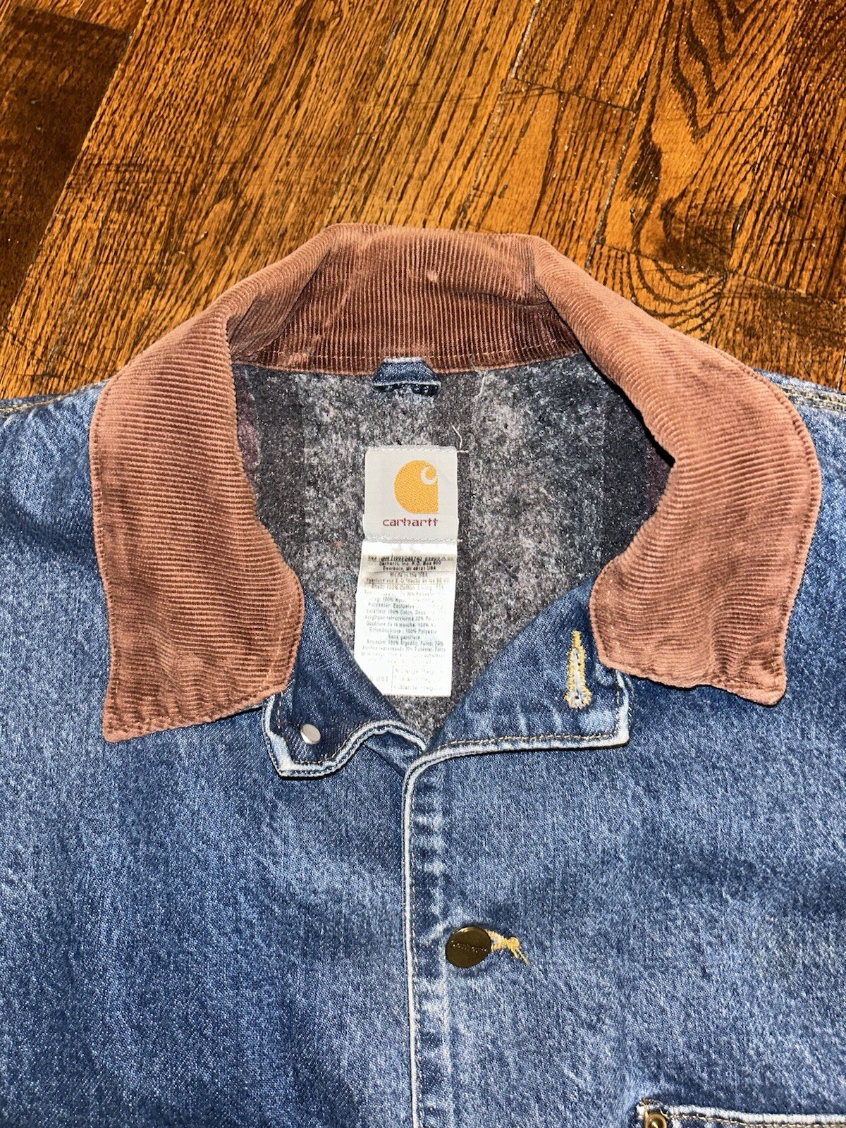 Blue denim Carhartt C59 chore coat with brown suede collar, gray lining, and visible Carhartt logo patch on chest.