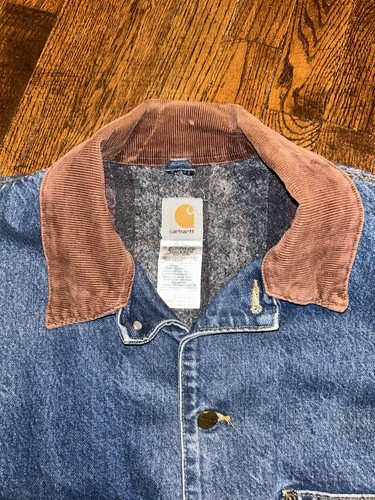 Blue denim Carhartt C59 chore coat with brown suede collar, gray lining, and visible Carhartt logo patch on chest.