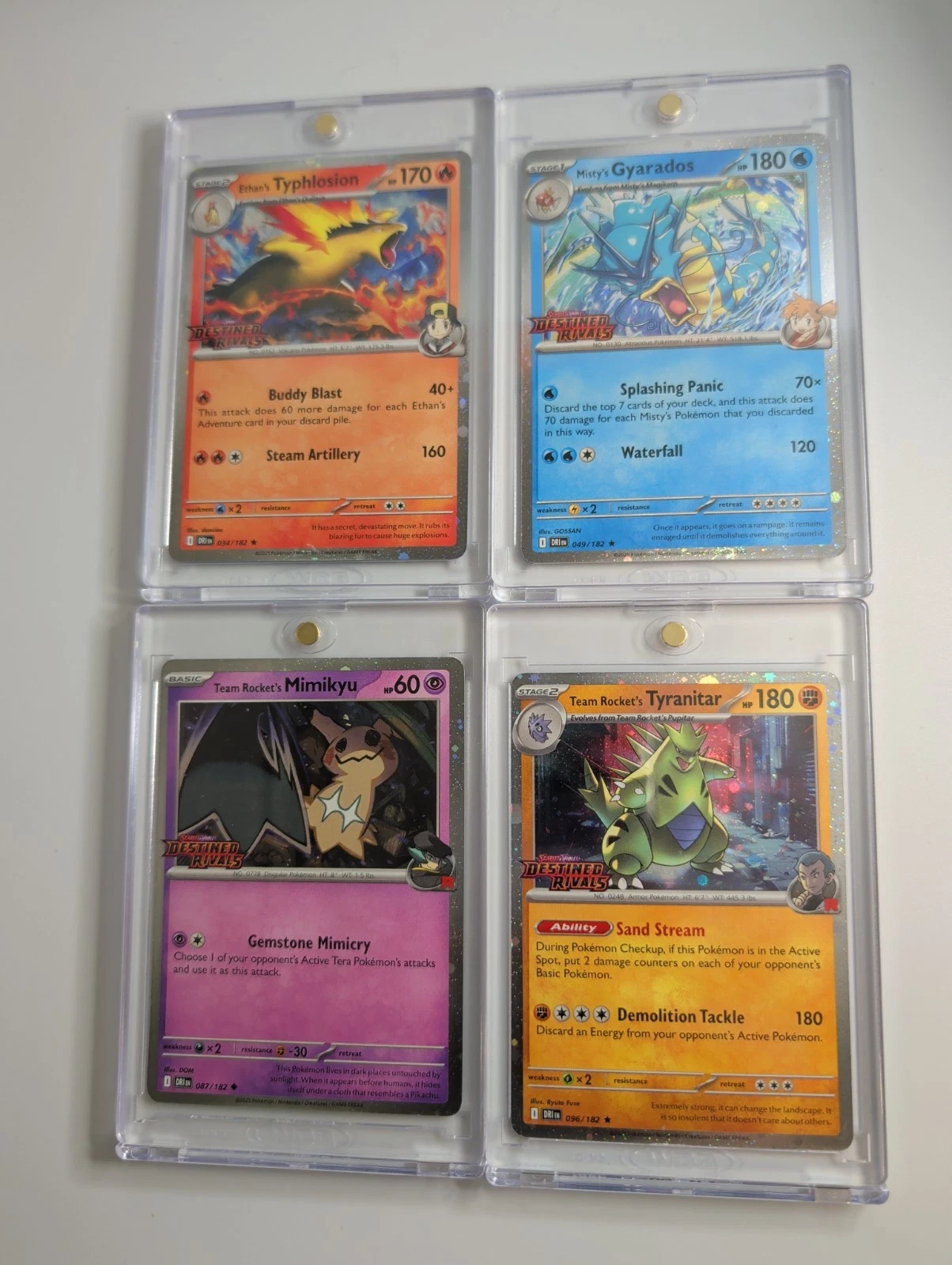 Four Pokemon cards in protective sleeves