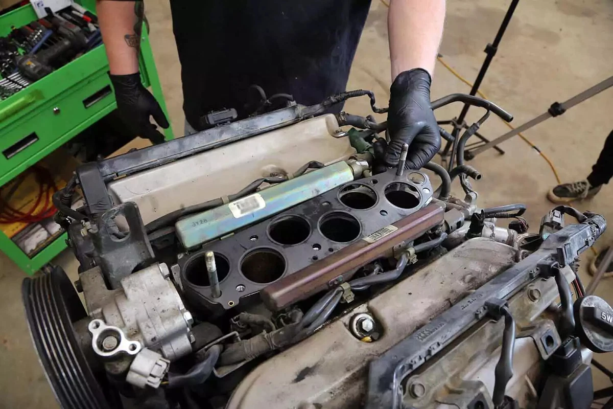 A mechanic preps the sealing surface, using a razor blade to remove residue from the old intake gasket.