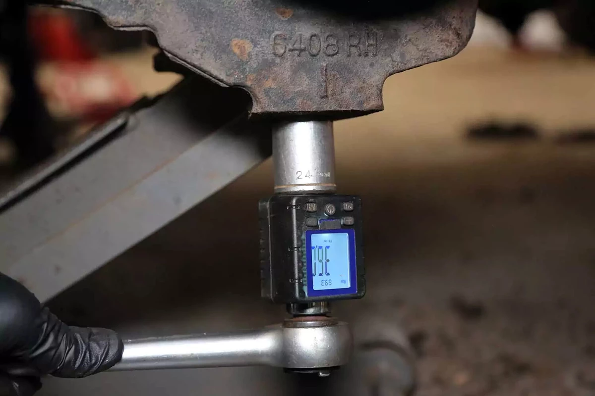 A mechanic uses a torque gauge and socket wrench to tighten the castle nut to factory specifications.