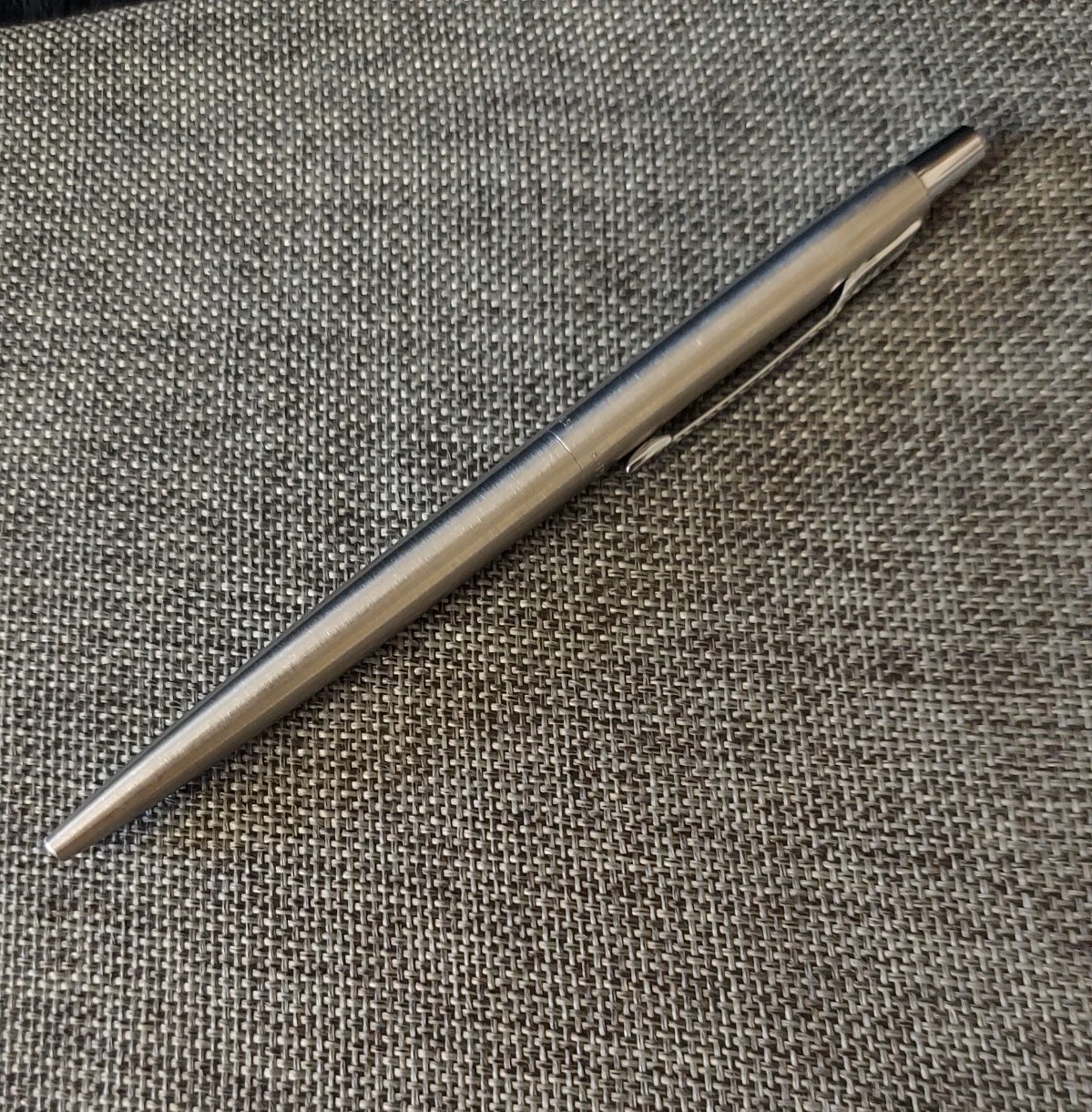 Silver Parker vintage ballpoint with blue ink, made in USA, on textured gray fabric background.
