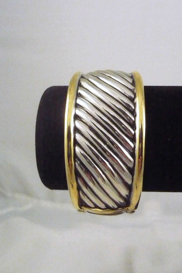Silver tone hinged bangle bracelet with gold edges and curved center design-image