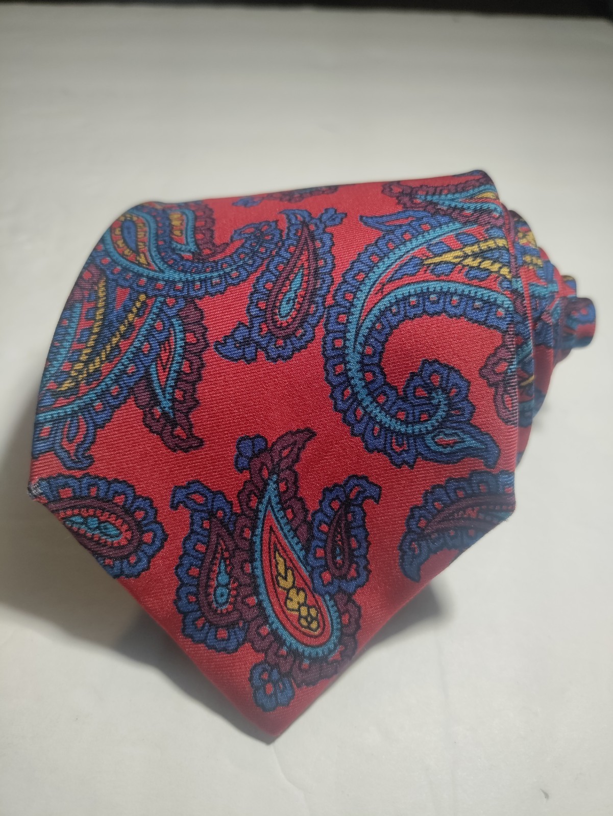 Red ETRO silk tie with yellow and blue paisley pattern, made in Italy, displayed against a plain white background.