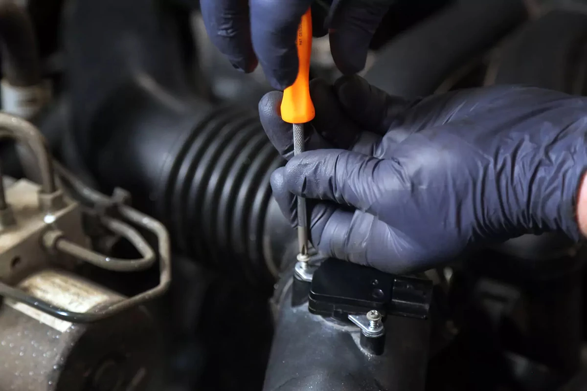 Mechanic using a screwdriver to fasten an MAF sensor.