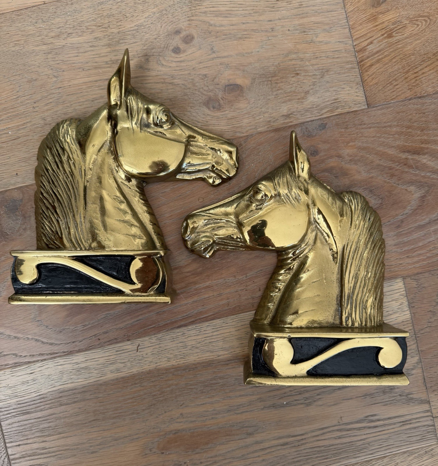 Pair of brass horse head bookends with dark patina, mounted on square bases.