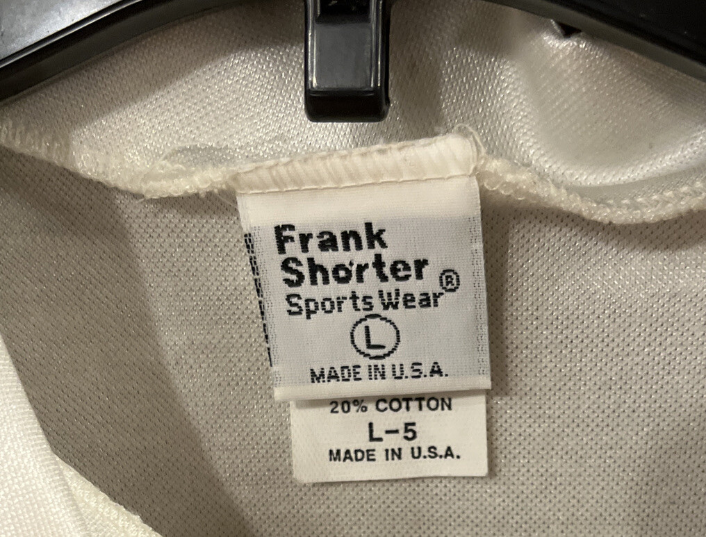 White cotton Frank Shorter Sports Wear cycling jersey, size L, with black tag reading “Made in U.S.A.”