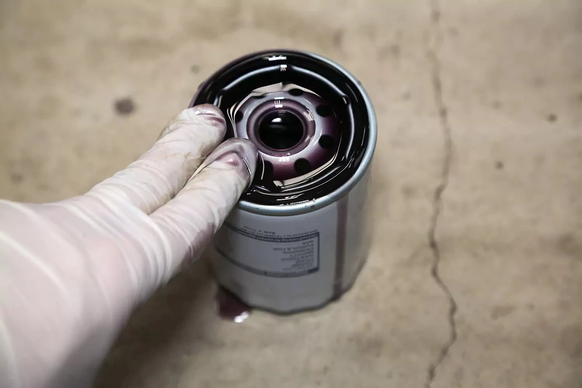A mechanic using their fingers to oil a filter gasket.