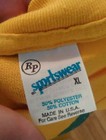 Yellow NOS New Vintage 80’s Sportswear T-shirt with blue “Sportswear” label, white fabric, and green stitching.