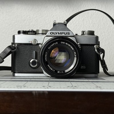 OLYMPUS OM-1n 35MM FILM MANUAL SLR CAMERA WITH 50MM F1.8 LENS READ