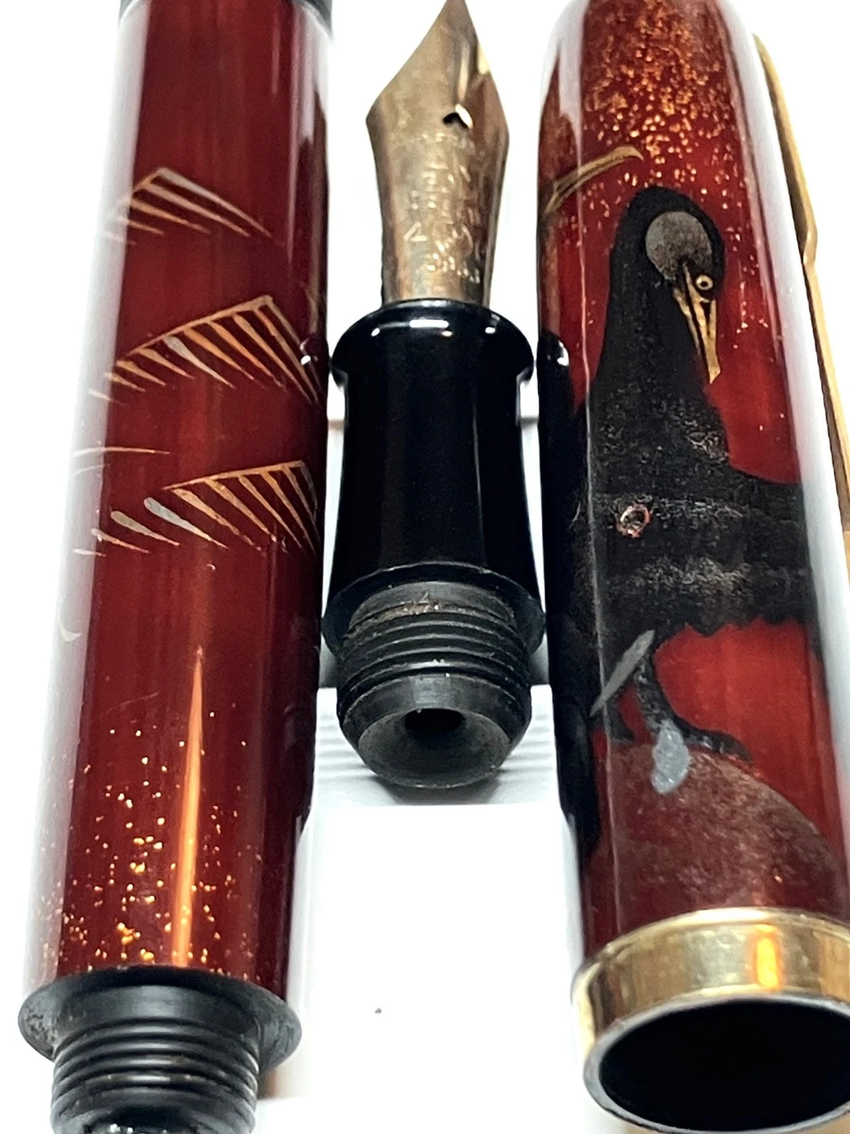 Vintage ink shut off fountain pen with gold nib, black body, red-gold accents, and gold bird design on barrel and body.