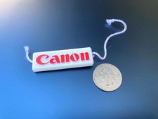 Canon camera advertising: tag / keychain / tiny plaque w/ string. Almost 2" long