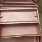 Pink plastic Caboodle makeup box with clear window, lower shelf, and visible seams.