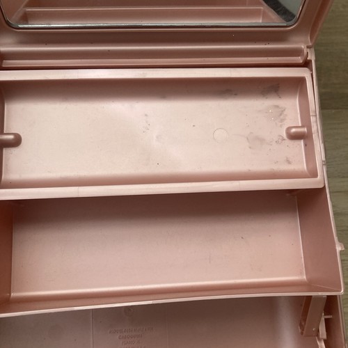 Pink plastic Caboodle makeup box with clear window, lower shelf, and visible seams.