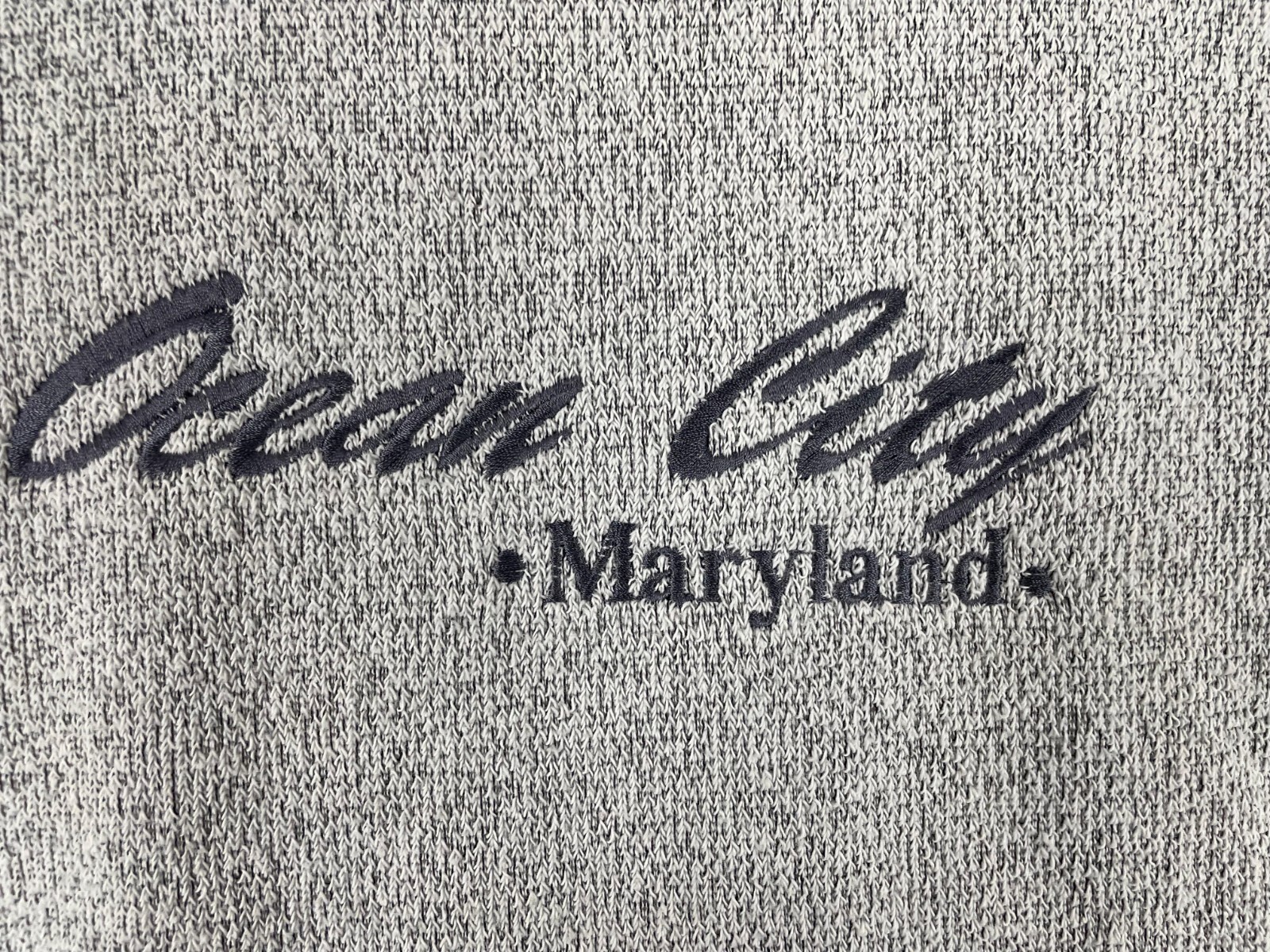 Gray vintage pullover sweater with navy “Ocean City Maryland” text and wavy line accents on chest and shoulders.