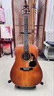 Brown acoustic guitar with f-holes, silver hardware, and visible scratches, S/N 375511, on stand in living room.