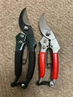 a set of pruner secateurs, one metal handle and another one plastic handle