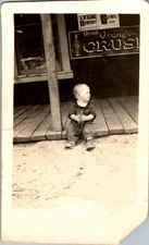 1920s Child on General Store Porch with Crush Soda & Sheriff Signs Photograph