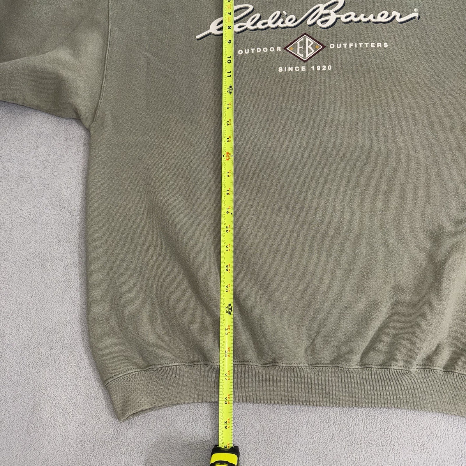 Gray vintage Eddie Bauer sweatshirt size L with yellow vertical measuring tape and black “Eddie Bauer Outfitting Since 1920” text.