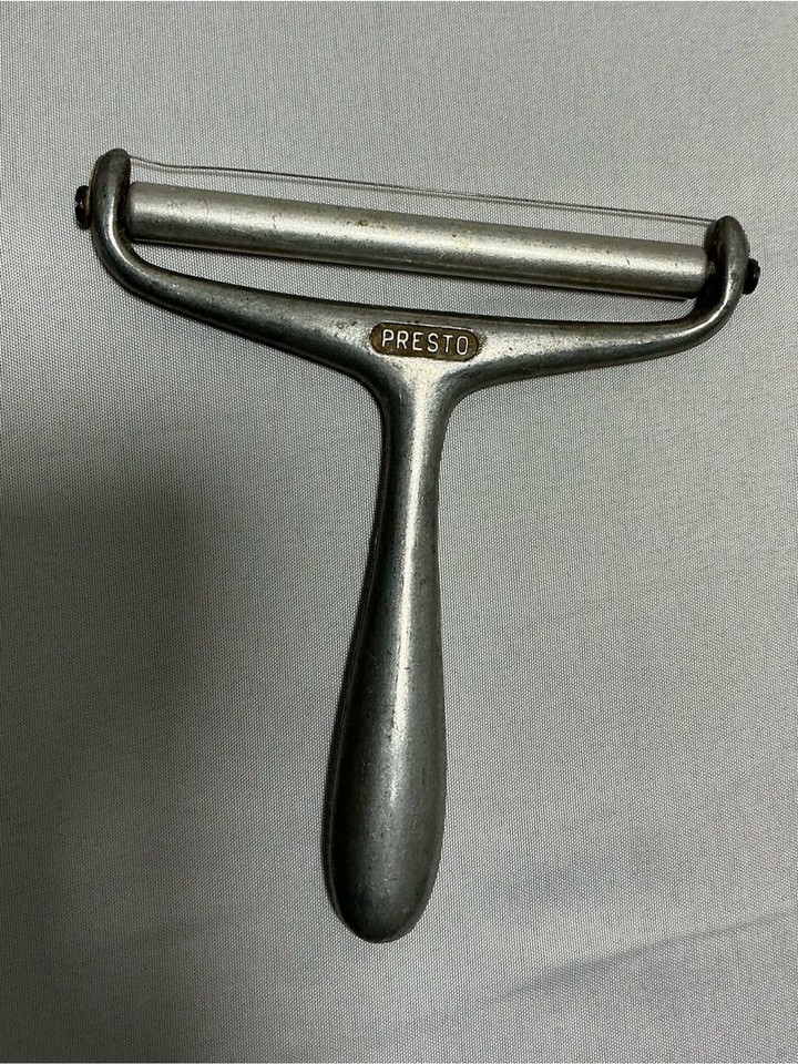 A vintage Presto aluminum wire-and-blade cheese slicer — a beautifully simple, industrial-looking retro gadget that still works perfectly and looks great on a charcuterie board.