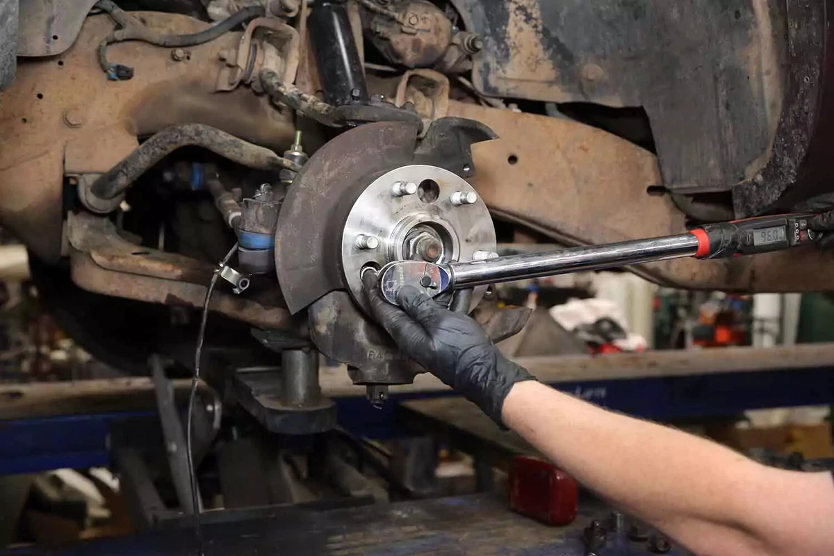A mechanic tightens the wheel hub bolts with a torque wrench.
