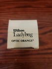 White rectangular Wilson Ladybug box labeled “Optic Orange” with black logo and orange ladybug graphics on wooden surface.