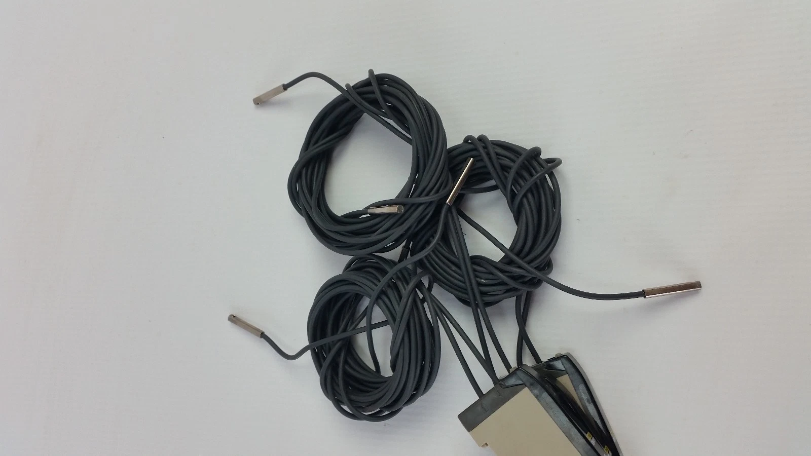 Coiled fiber-optic cables with metal sleeve tips attached to the E3X-NH11 amplifiers