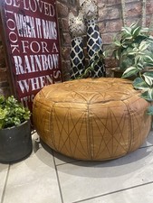Vintage Moroccan-style brown leather pouf often used for seating or a foot rest.